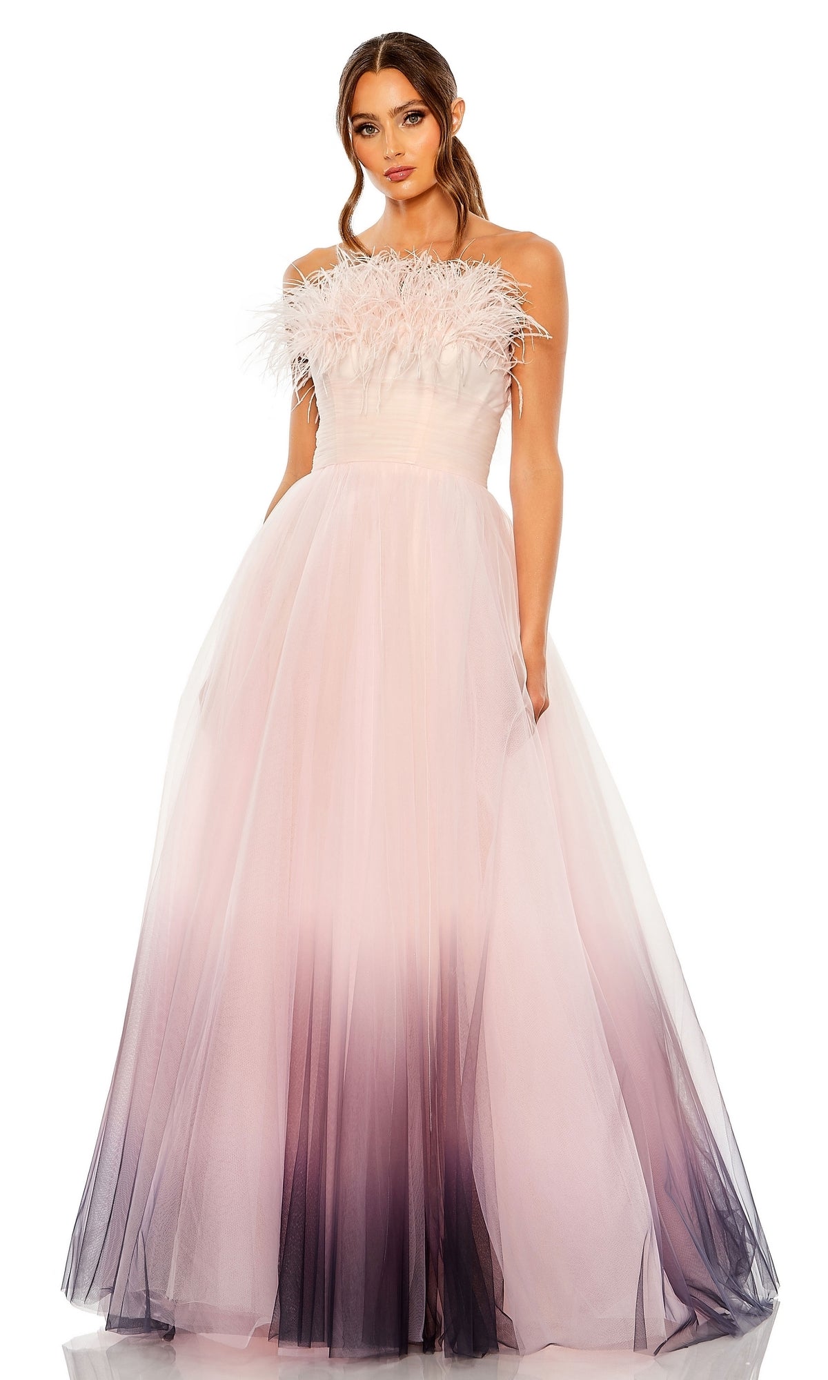 A woman wears the Long Formal Dress 20557 by Mac Duggal, a strapless ball gown with a tulle skirt in pink and purple ombre shades and an ombre feather-trimmed bodice.